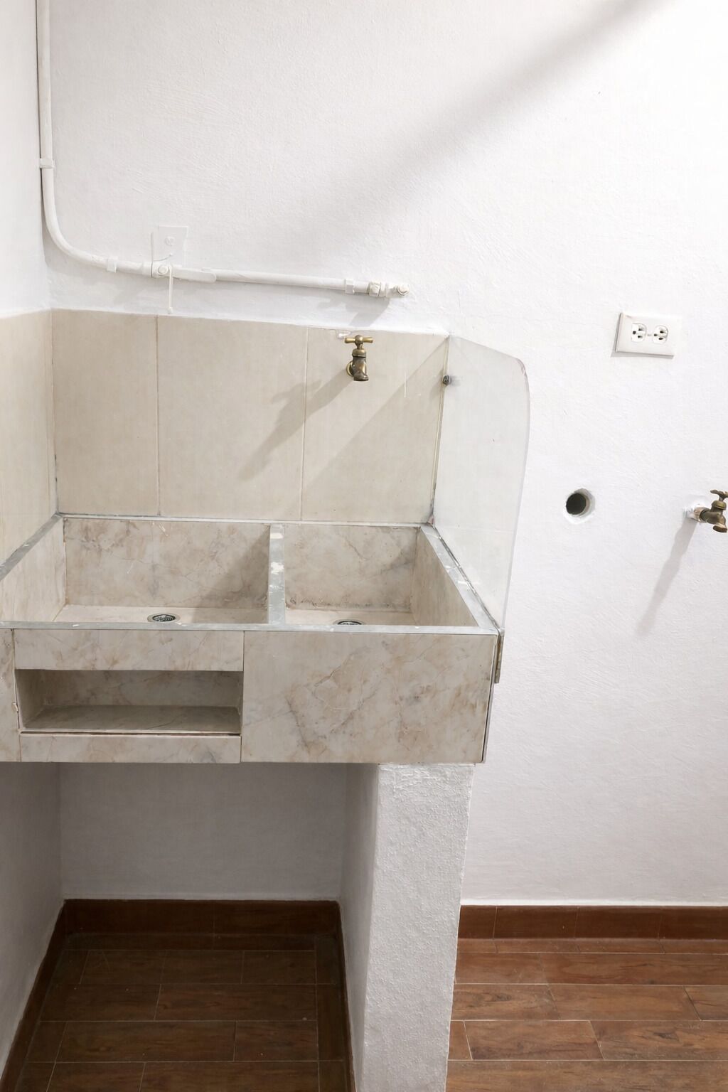 A bathroom with a marble sink, a white wall, and a wooden floor.