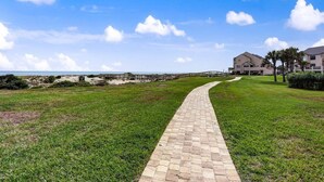 Um caminho pavimentado que leva a um edifício com vista para a praia.