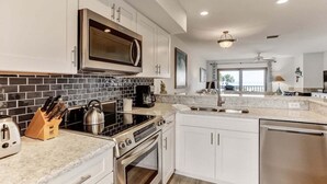 Cozinha moderna com armários brancos, fogão de aço inoxidável e backsplash de azulejo preto.