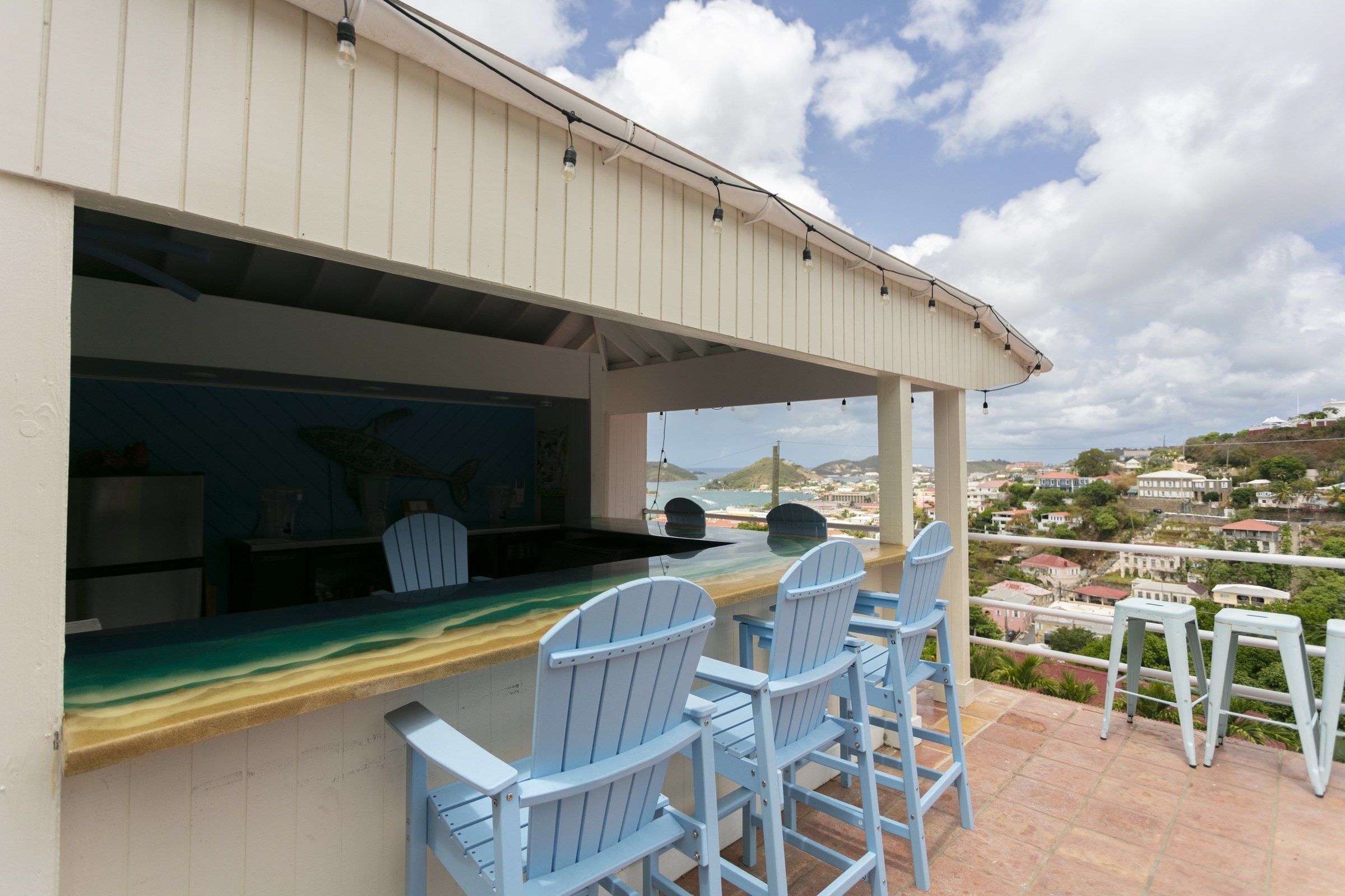 A seaside bar with a view of the ocean and a town in the distance.