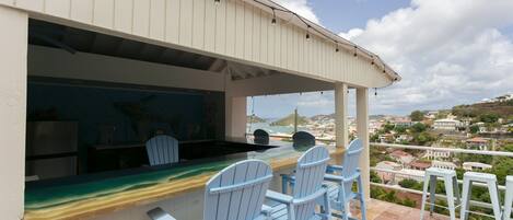 A seaside bar with a view of the ocean and a town in the distance.