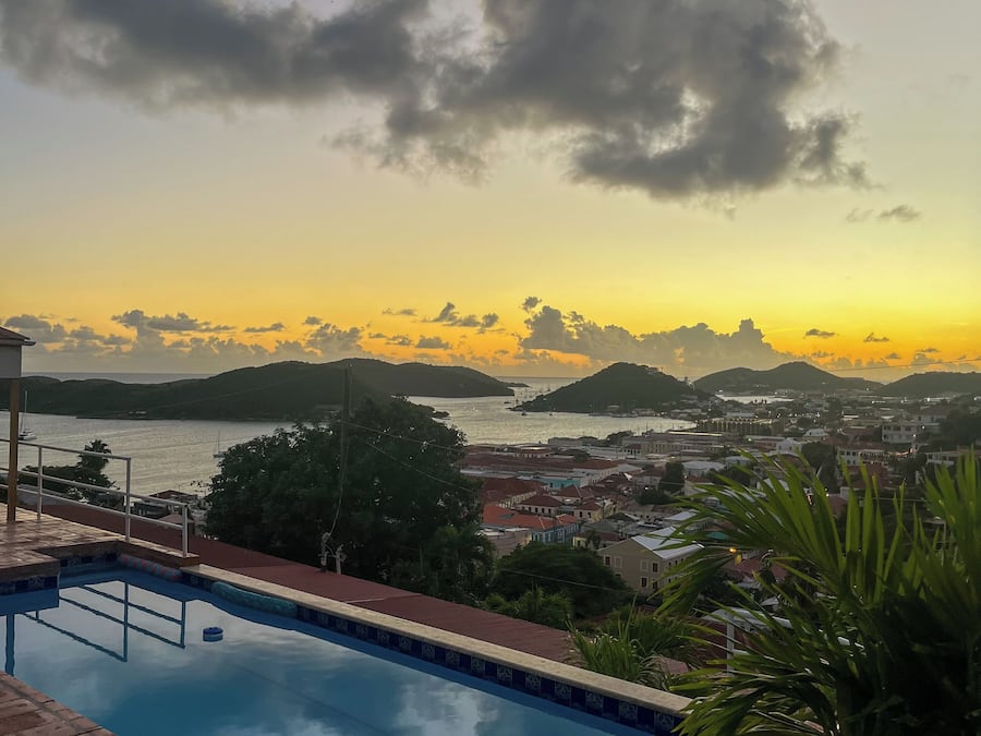 Ein Schwimmbecken mit Blick auf eine Stadt und ein Gewässer bei Sonnenuntergang.