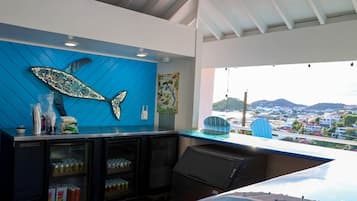 A bar area with a large fish decoration, a map, and a view of a coastal town.