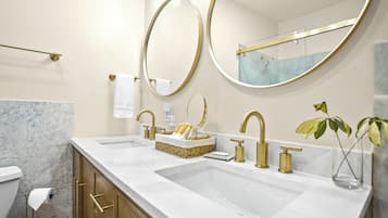 Une salle de bain moderne avec deux vasques, des robinets dorés et des plans de toilette en marbre.