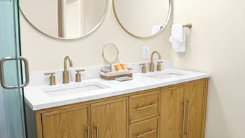 A bathroom with two sinks, wooden cabinets, and two round mirrors.