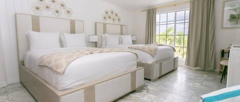 A hotel room with two beds, a large window, and a view of greenery outside.