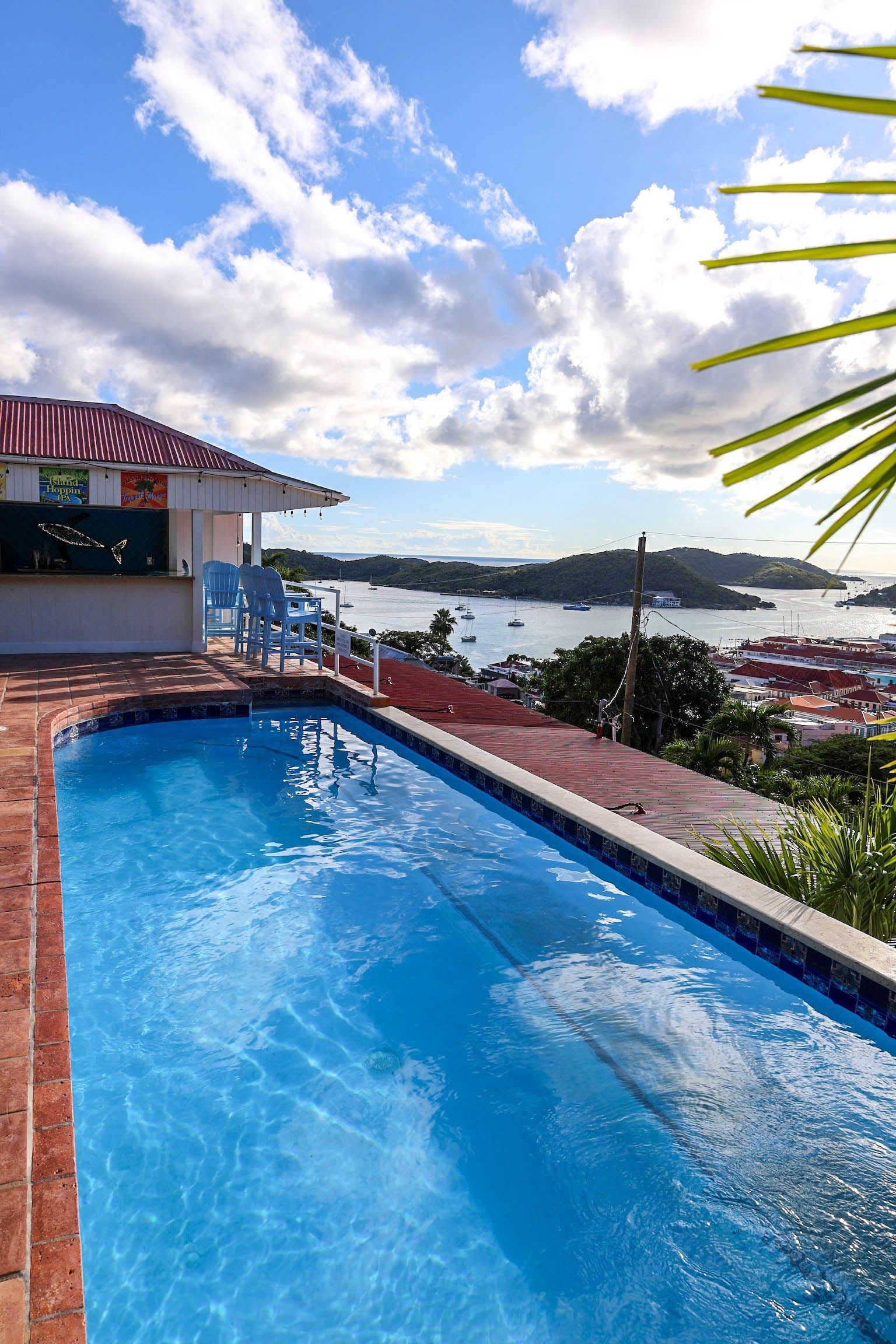 A swimming pool with a view of boats and hills in the background.