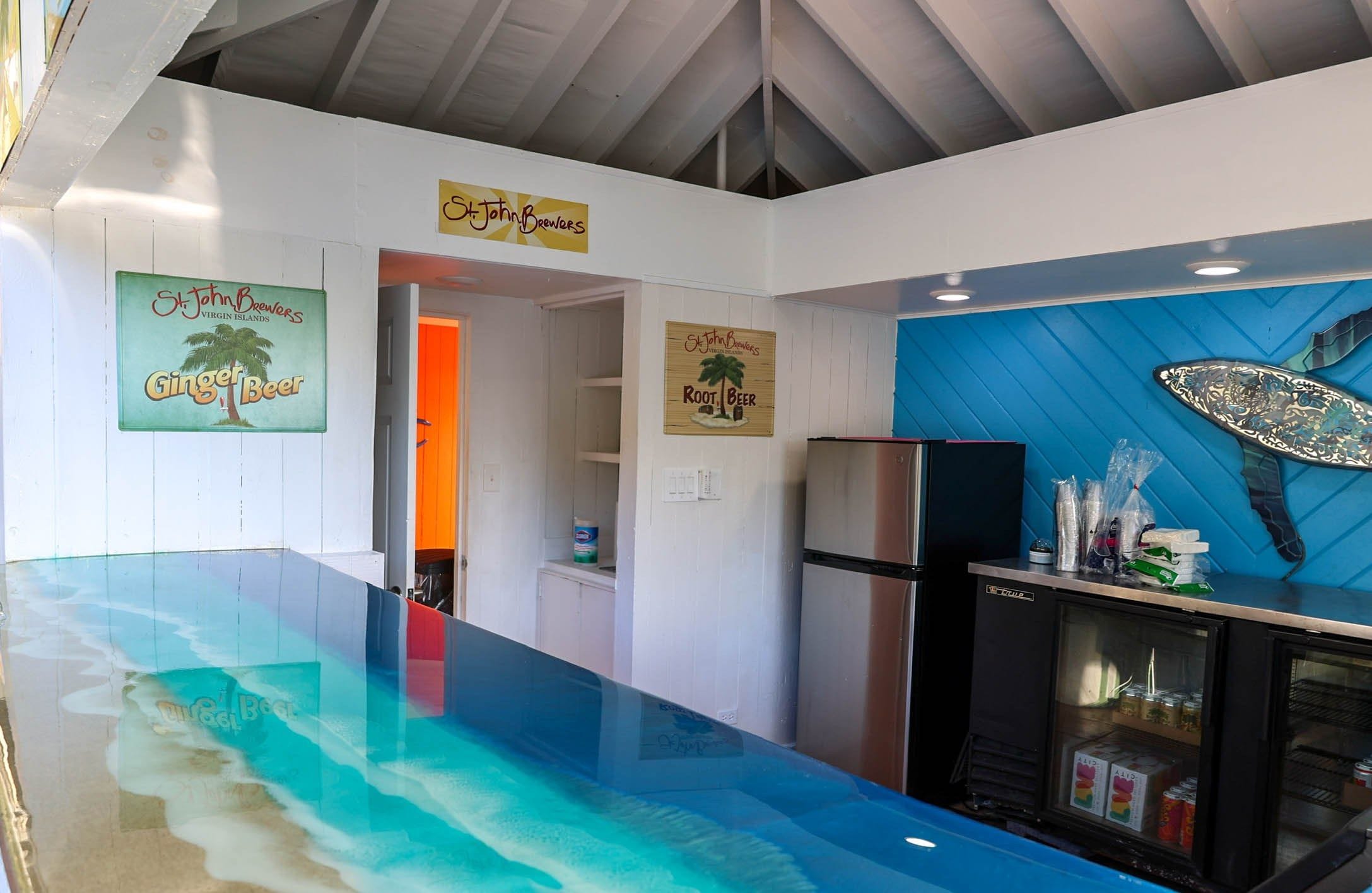 Una cocina con encimera azul, un refrigerador y un congelador. Hay letreros en la pared que sugieren una temática relacionada con la cerveza.