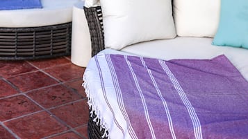Two outdoor seating areas with white canopies and cushions, set against a backdrop of greenery and pink flowers.