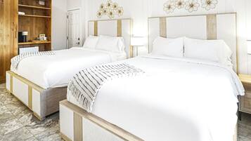 A hotel room with two beds, wooden headboards, a wooden wardrobe, and a marble floor.