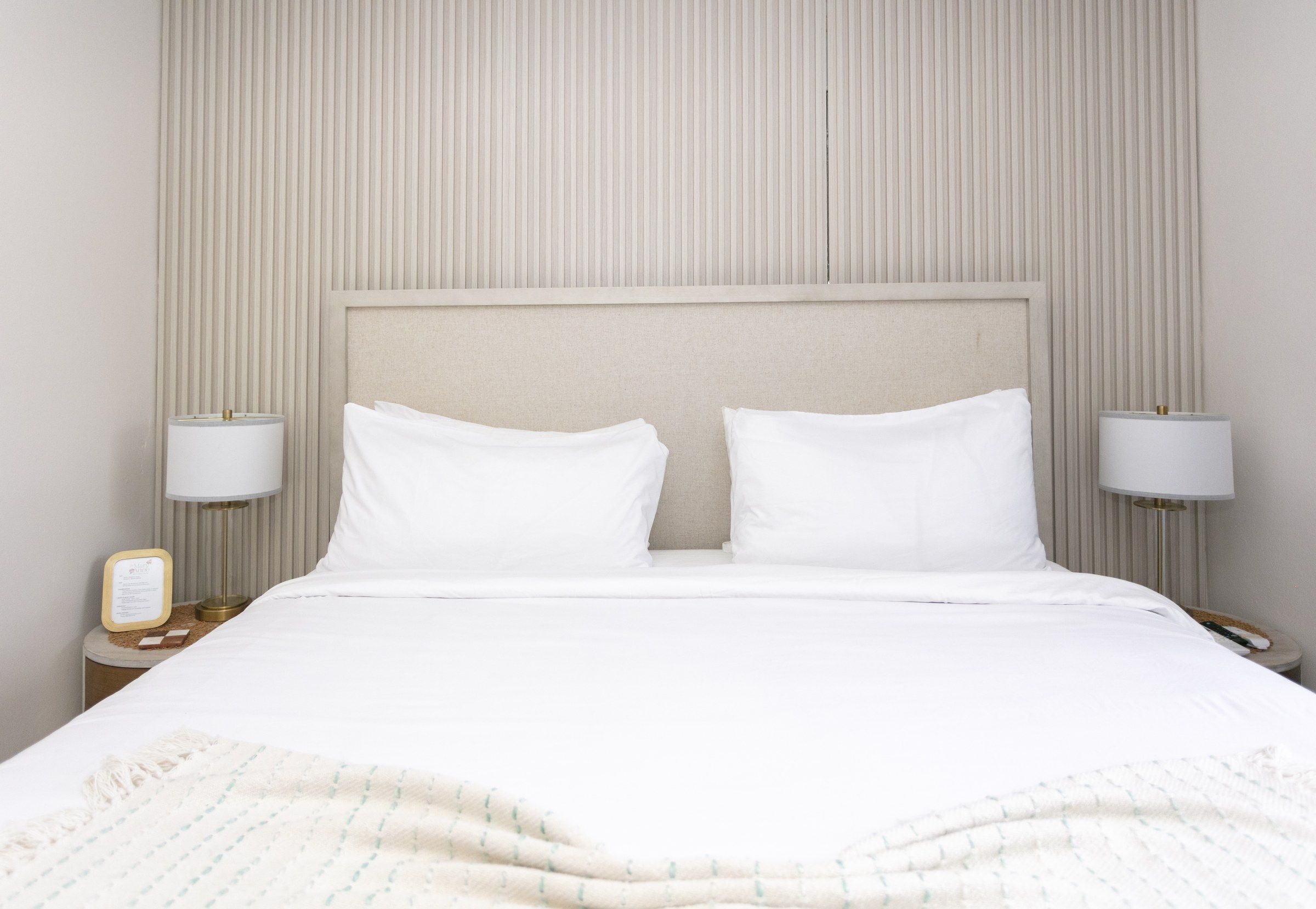Une chambre d’hôtel avec un lit, deux lampes de chevet et une table de chevet avec une horloge.
