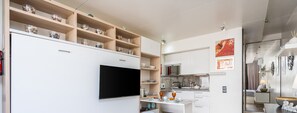 Eine moderne Küche mit eingebauten Regalen, einem Flachbildfernseher und einem Essbereich mit Tisch und Stühlen.