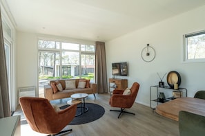 A spacious living room with a large window, a sofa, a coffee table, and a TV.