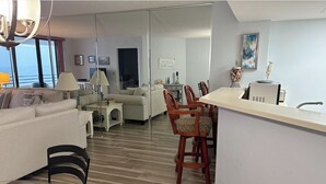 A modern hotel room with a living area, dining space, and a view of the sea. - Oceanfront Sand Dollar Condo 601 (Daytona Beach Shores)
