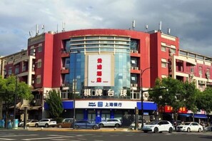 A multi-story building with a prominent red and blue facade, featuring a large sign with Chinese characters. - Yuntu Hotel (Shanghai Jinshan Bailian City Beach) (Shanghai)