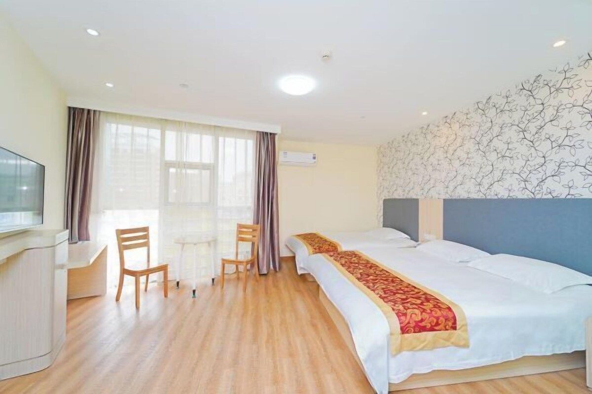 Una habitación de hotel con cama, escritorio, dos sillas y televisor.