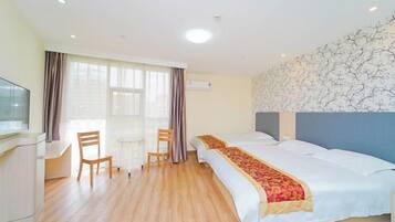 A hotel room with a bed, a desk, two chairs, and a TV.