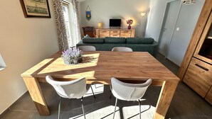 Un comedor con una mesa de madera y dos sillas, un sofá verde y un televisor al fondo.