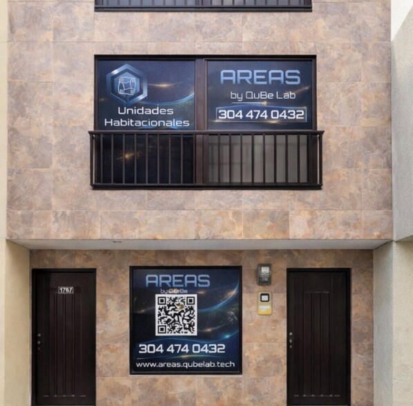 A building facade with two signs advertising 'AREAS by QuBe Lab' and a QR code.