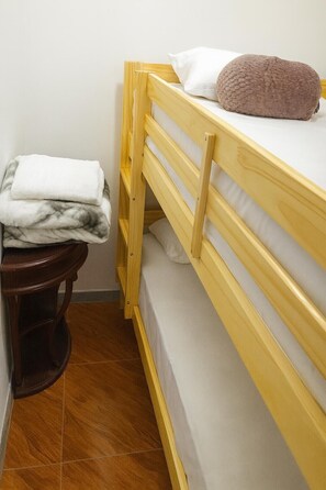 A bunk bed with a wooden frame, a pillow, and a folded blanket on the top bunk.