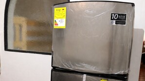 Un refrigerador de acero inoxidable con compartimento congelador y dispensador de agua, y una etiqueta de garantía de 10 años.