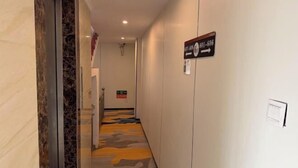 Un couloir avec un panneau indicateur, une moquette à motifs et un interrupteur fixé au mur.