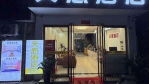L’entrée d’un hôtel, avec un comptoir d’accueil, une porte vitrée et une enseigne.