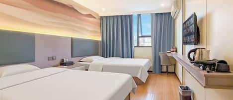 Habitación de hotel con dos camas, un escritorio, una silla, un televisor y una ventana con cortinas.