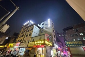 A multi-story building with illuminated signage, a visible entrance, and a street-level shop. - Nanning Tian'en Hotel (Xiuxiang Metro Station, Guangxi University Branch) (Nanning)