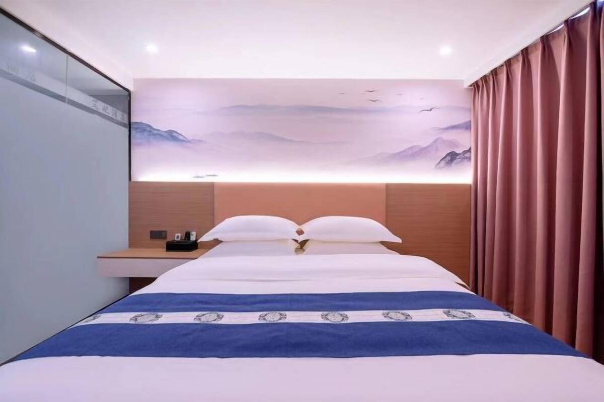 A hotel room with a bed, a nightstand, and a wall-mounted artwork.