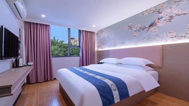 Une chambre d’hôtel avec un lit, une télévision, un bureau et une fenêtre avec des rideaux.