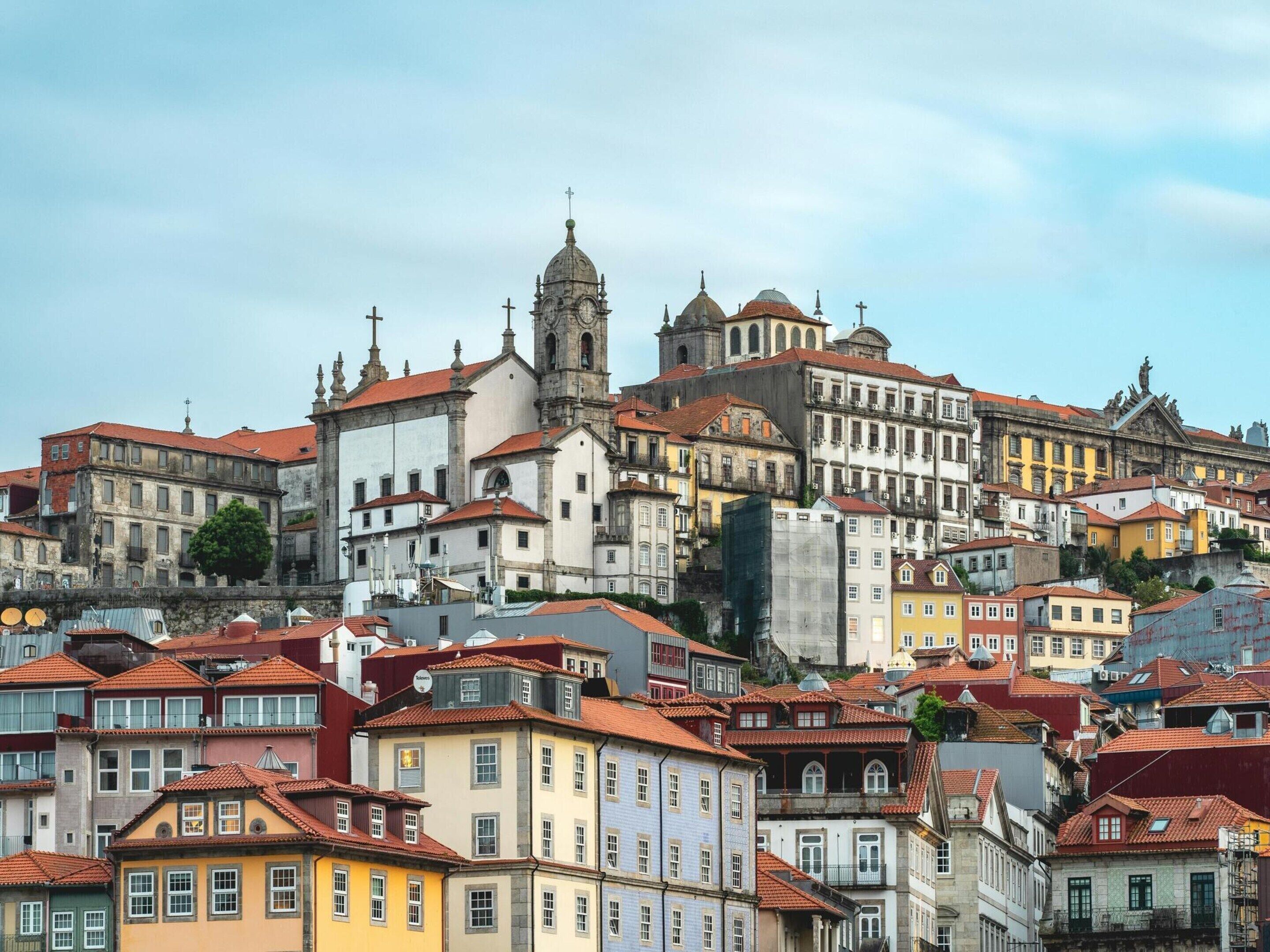 A historic cityscape with a prominent church featuring a clock tower and multiple crosses.