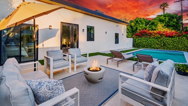 A modern outdoor living area with a fire pit, lounge chairs, and a pool.