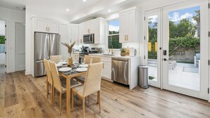 A modern kitchen with white cabinets, stainless steel appliances, and a dining area with a table set for four.