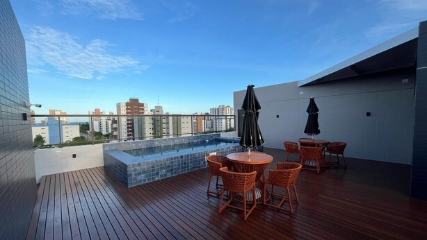 A rooftop terrace with a pool, wicker furniture, and a city view.