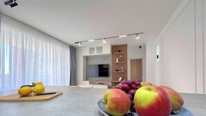 Ein modernes Wohnzimmer mit einem großen Flachbildfernseher, einer Holzunterhaltungsecke und einem Essbereich mit einer Obstplatte.