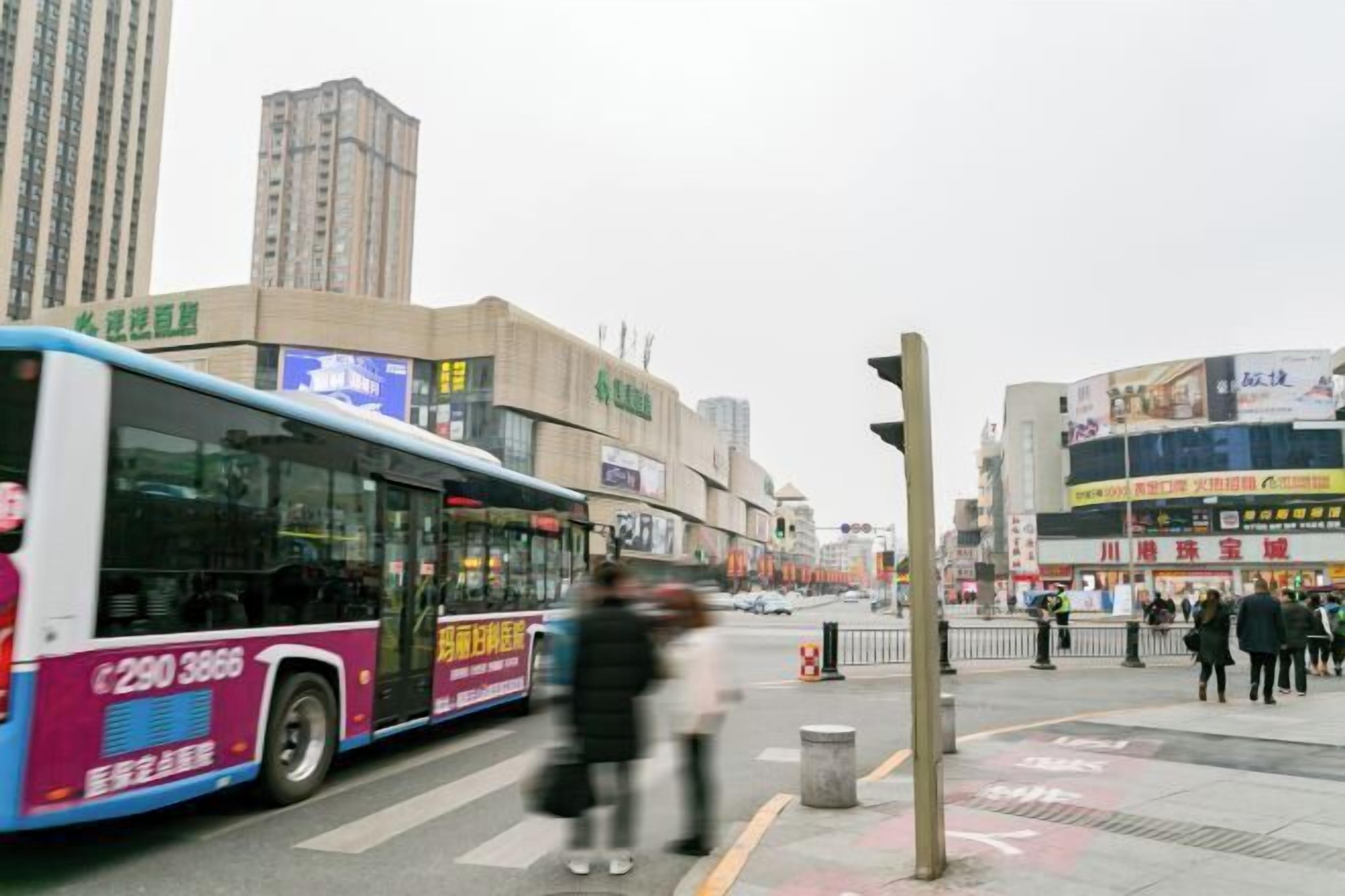 Une rue de la ville avec un autobus, des piétons et des immeubles commerciaux.