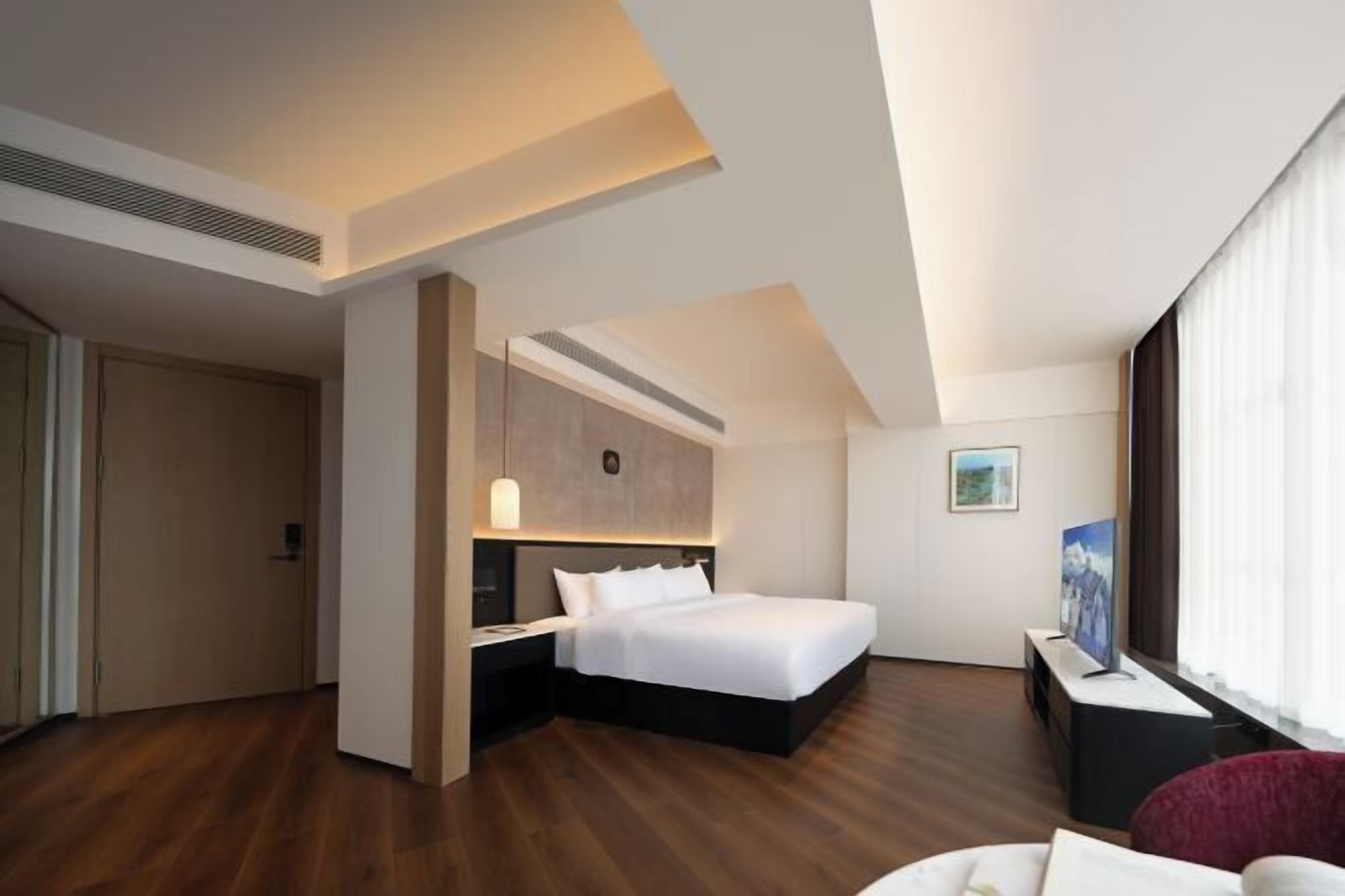 Una habitación de hotel moderna con una cama grande, un escritorio, una silla y un televisor.