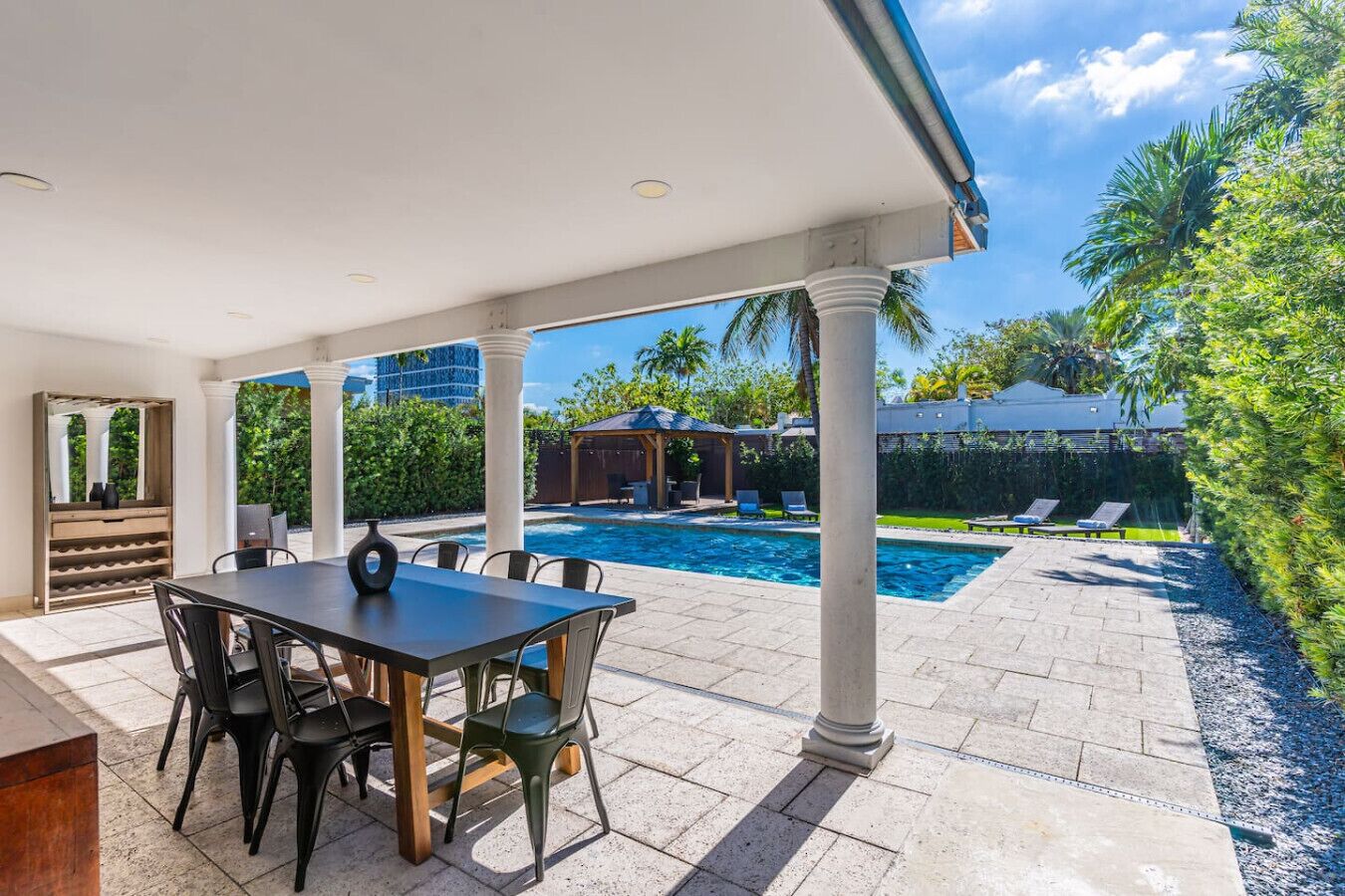 Eine überdachte Terrasse mit Pool, Sitzgelegenheiten im Freien und einer Pergola.