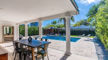 Eine überdachte Terrasse mit Pool, Sitzgelegenheiten im Freien und einer Pergola.