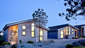 Una casa moderna de dos pisos con entrada de grava, revestimiento de madera y ventanas grandes.
