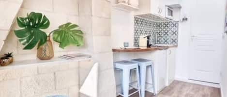 A compact kitchen with a tiled backsplash, a small bar area with stools, and a refrigerator.