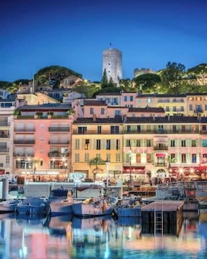 Un port esportiu amb embarcacions amarrades, una torre al fons i edificis amb balcons.