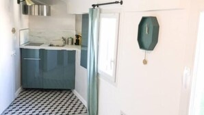 Une cuisine compacte au design moderne, dotée d’un évier encastré, de placards et d’une fenêtre avec un rideau.
