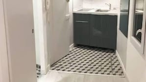 Une cuisine de taille réduite avec un carrelage à motifs, un évier et des meubles de couleur sombre.
