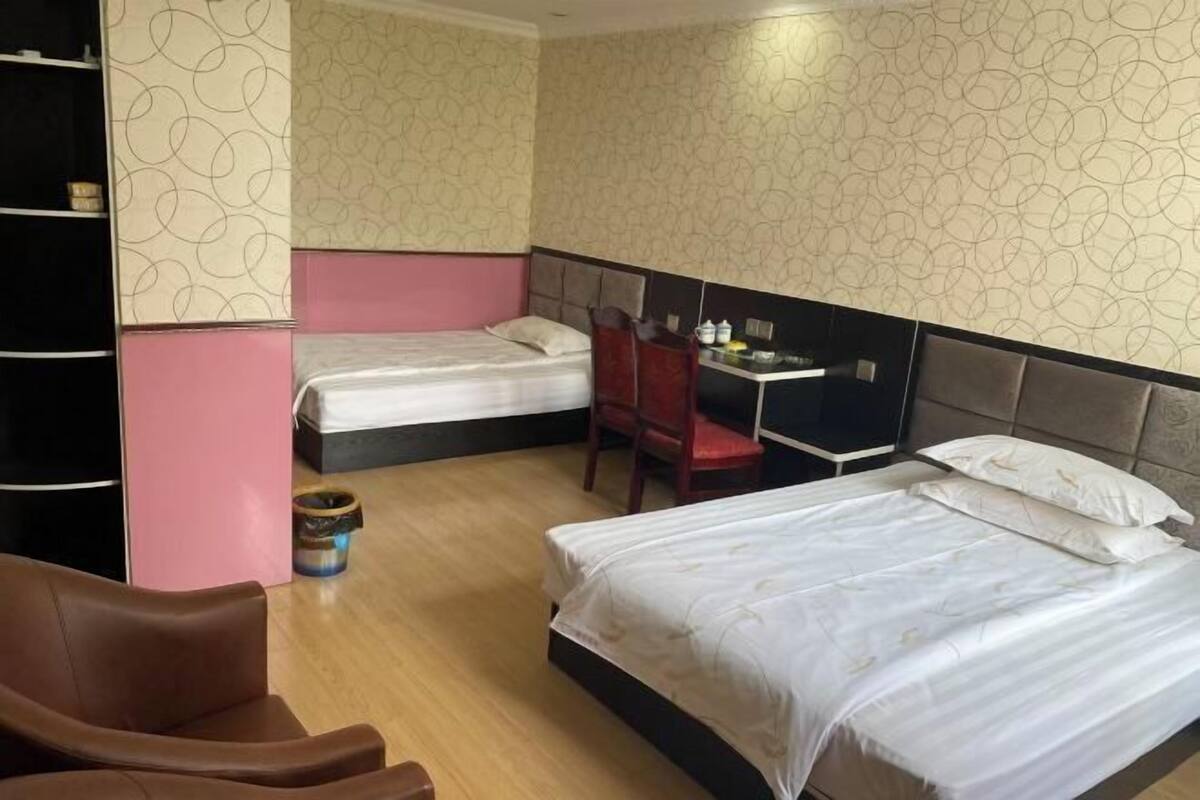Una habitación de hotel con dos camas, un escritorio, una silla y una estantería.