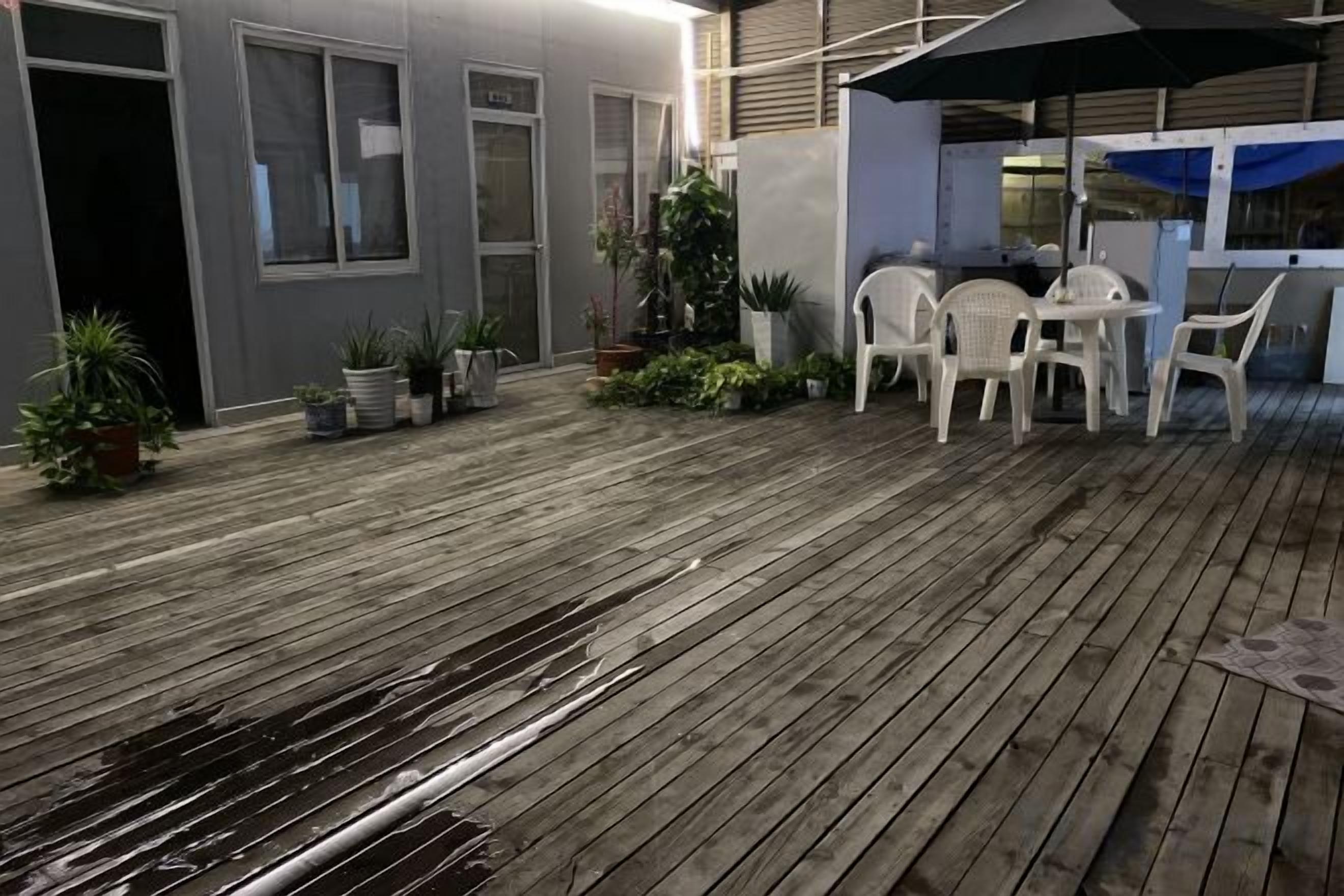 Une terrasse en bois avec des sièges d’extérieur et des plantes en pot.