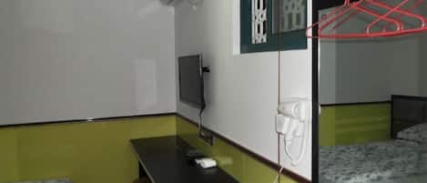 A room with bunk beds, a desk, a chair, a TV, and a mirror.