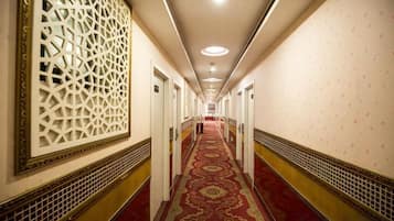 A long hallway with patterned walls and a red carpet, leading to a door at the end.