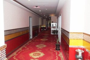 A corridor with a red carpet, doors on both sides, and a trash bin on the right. - Jinshang Hostel (Shanghai)